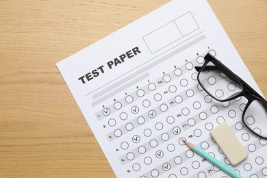 Photo of Answer sheet, eraser, pencil and glasses on wooden table, flat lay. Student passing exam