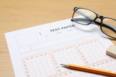 Photo of Answer sheet, eraser, pencil and glasses on wooden table, closeup. Student passing exam