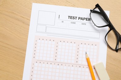 Photo of Answer sheet, eraser, pencil and glasses on wooden table, flat lay. Student passing exam