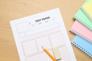 Photo of Answer sheet, eraser, pencil and notebooks on wooden table, flat lay. Student passing exam