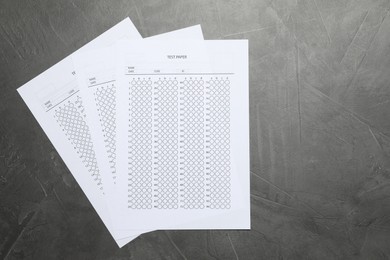 Photo of Answer sheets on gray textured table, flat lay. Student passing exam