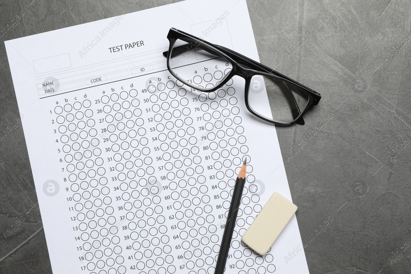 Answer sheet, glasses, pencil and eraser on gray textured table, flat lay. Student passing exam Photo of Answer sheet, glasses, pencil and eraser on gray textured table, flat lay. Student passing exam