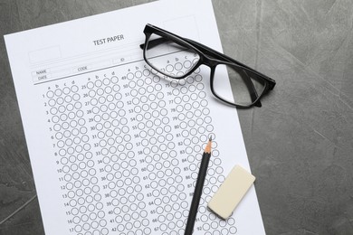 Photo of Answer sheet, glasses, pencil and eraser on gray textured table, flat lay. Student passing exam