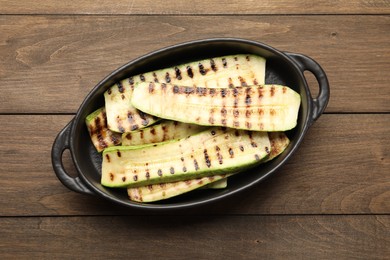 Photo of Delicious grilled courgette slices in baking dish on wooden table, top view