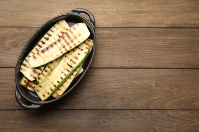 Photo of Delicious grilled courgette slices in baking dish on wooden table, top view. Space for text
