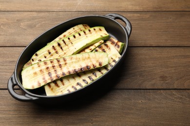 Photo of Delicious grilled courgette slices in baking dish on wooden table, above view
