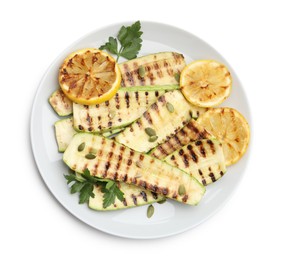 Photo of Delicious grilled courgette slices with pumpkin seeds, lemon and parsley isolated on white, top view