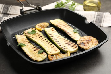 Photo of Delicious grilled courgette slices with garlic, lemon and parsley in pan on grey table, closeup