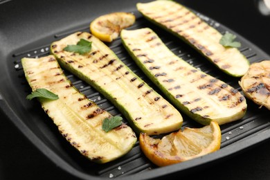 Photo of Delicious grilled courgette slices with salt, lemon and parsley in pan, closeup