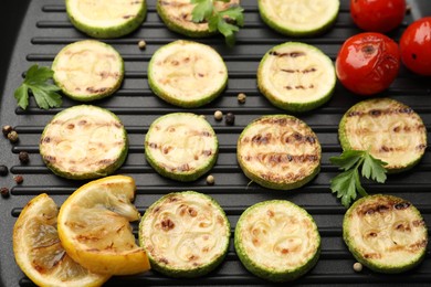 Photo of Delicious grilled courgette slices with tomatoes, lemon and parsley in pan, above view