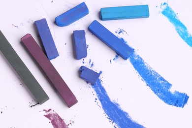 Photo of Colorful chalk pastels on white background, flat lay