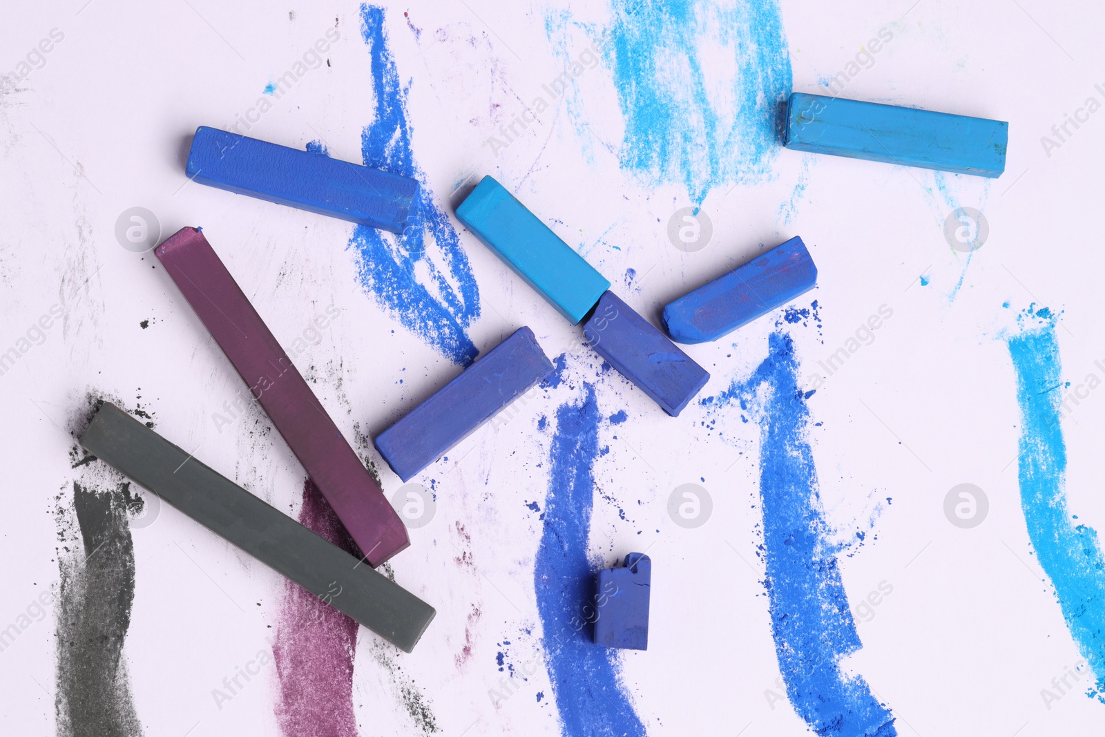 Colorful chalk pastels on white background, flat lay Photo of Colorful chalk pastels on white background, flat lay