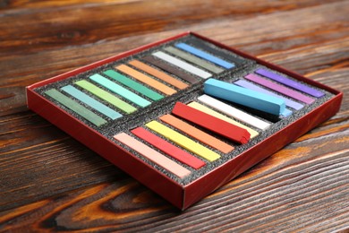 Photo of Set of colorful chalk pastels on wooden table