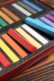 Photo of Set of colorful chalk pastels on wooden table, closeup
