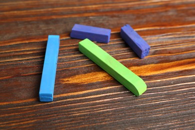 Photo of Colorful chalk pastels on wooden table, closeup