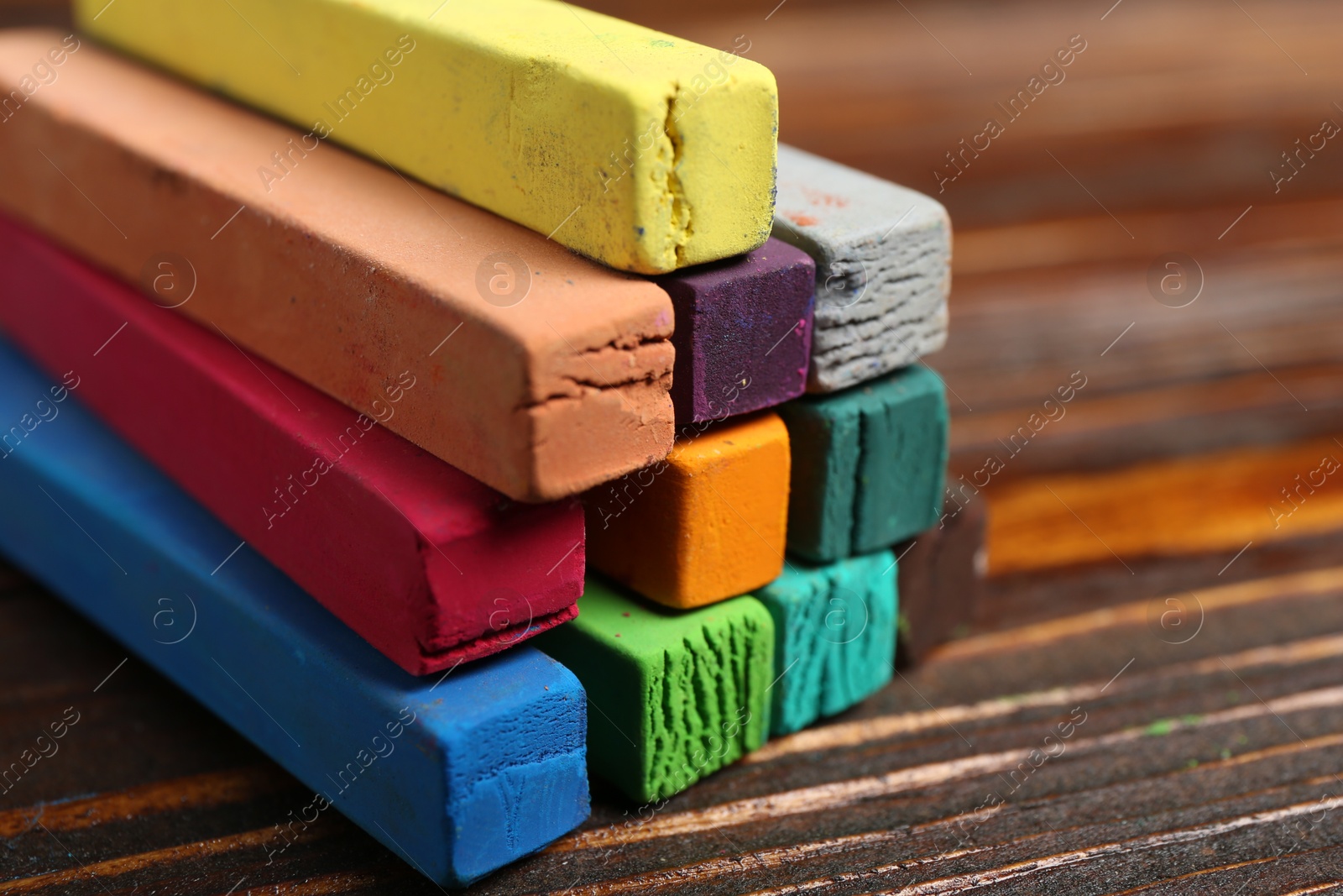 Photo of Colorful chalk pastels on wooden table, closeup