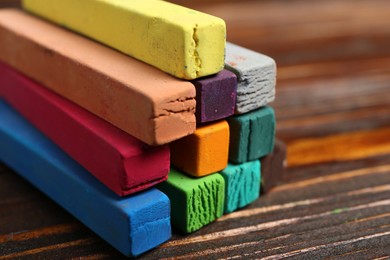 Photo of Colorful chalk pastels on wooden table, closeup