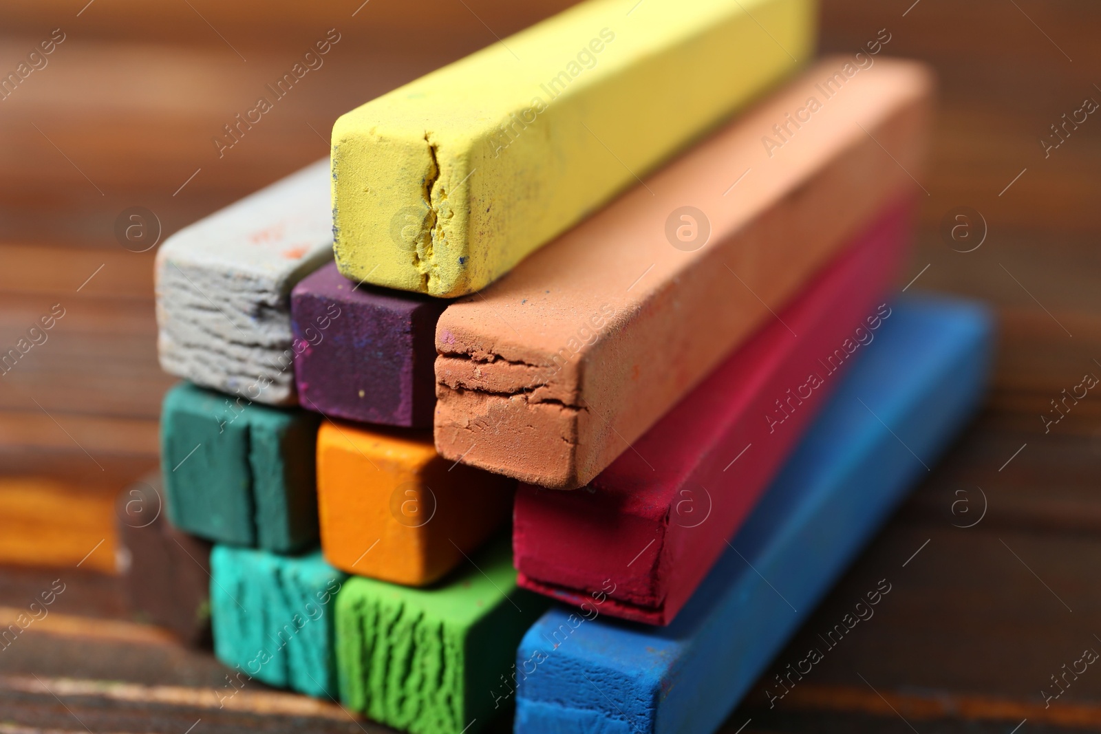 Photo of Colorful chalk pastels on wooden table, closeup