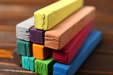 Photo of Colorful chalk pastels on wooden table, closeup