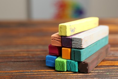 Photo of Colorful chalk pastels on wooden table, closeup. Space for text
