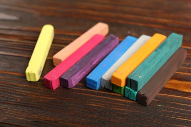 Photo of Colorful chalk pastels on wooden table, closeup