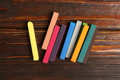 Photo of Colorful chalk pastels on wooden table, flat lay