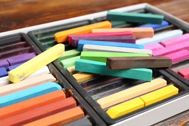 Photo of Set of colorful chalk pastels on wooden table, closeup