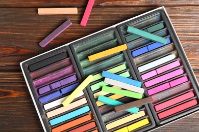 Photo of Set of colorful chalk pastels on wooden table, flat lay