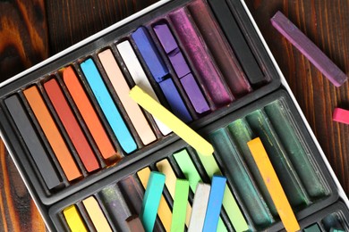 Photo of Set of colorful chalk pastels on wooden table, flat lay