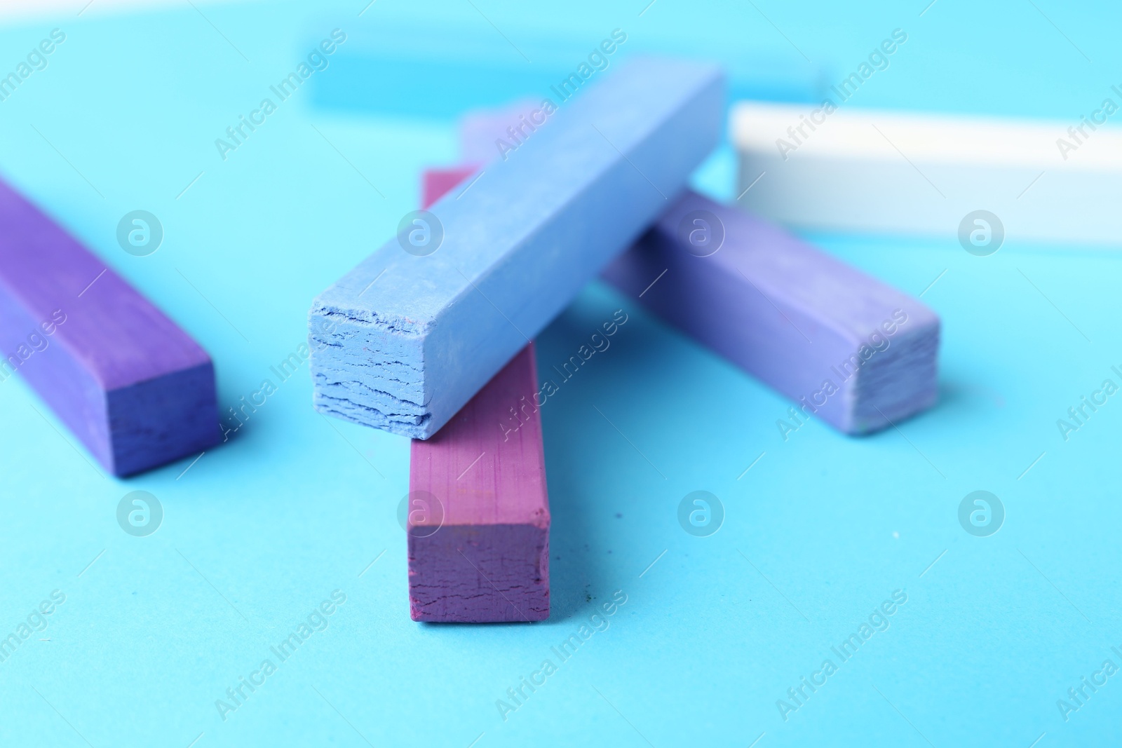 Colorful chalk pastels on light blue background, closeup Photo of Colorful chalk pastels on light blue background, closeup