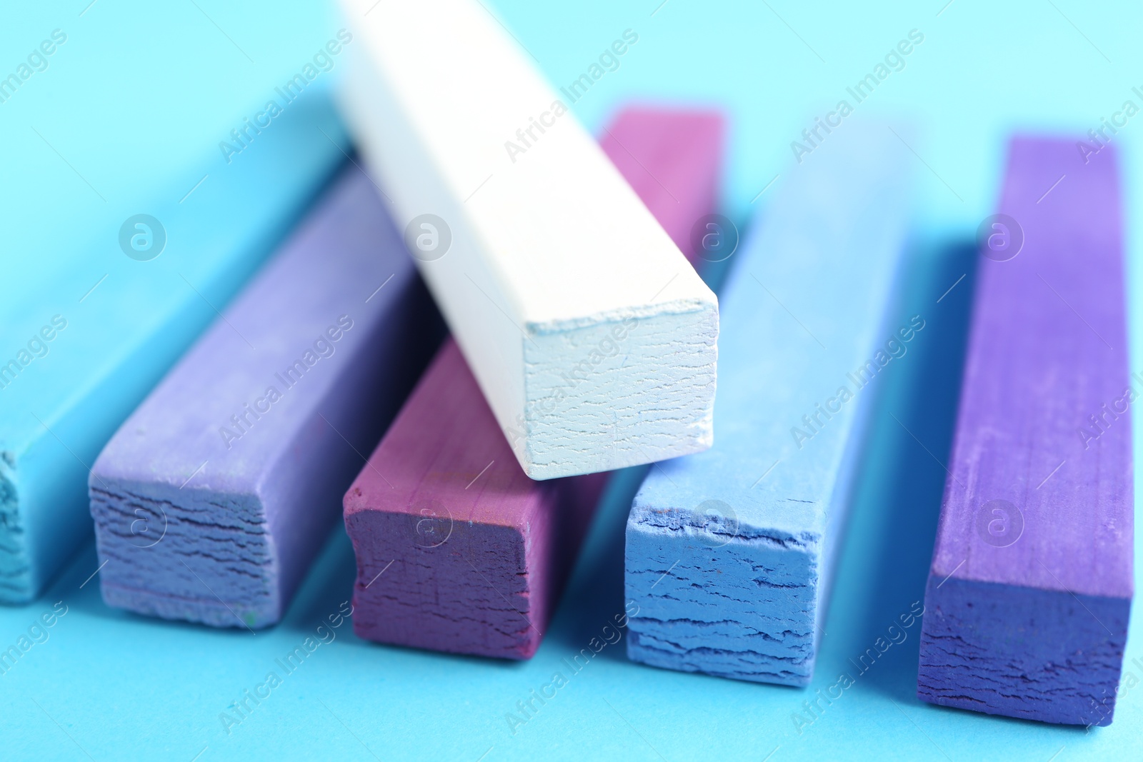 Colorful chalk pastels on light blue background, closeup Photo of Colorful chalk pastels on light blue background, closeup