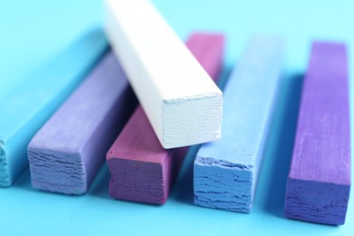 Photo of Colorful chalk pastels on light blue background, closeup