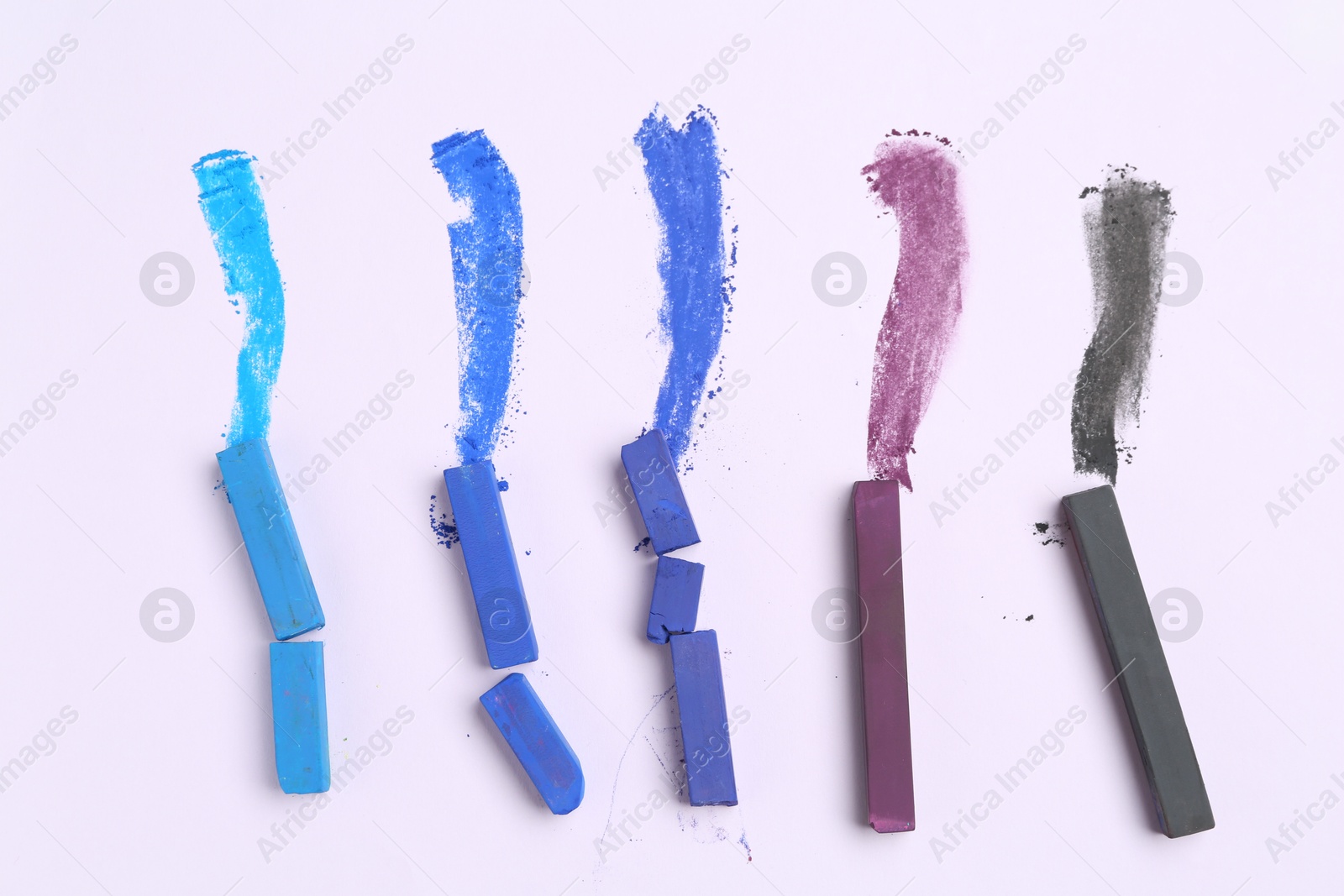 Colorful chalk pastels on white background, flat lay Photo of Colorful chalk pastels on white background, flat lay