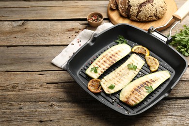 Photo of Delicious grilled courgette slices with spices and lemon in pan on wooden table, closeup