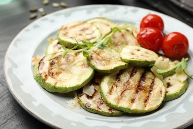 Photo of Delicious grilled courgette slices with tomatoes and microgreens on table, closeup