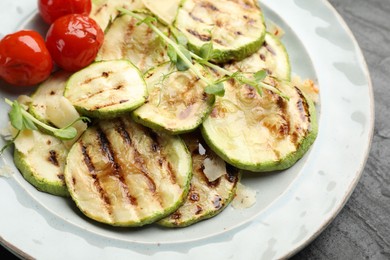 Photo of Delicious grilled courgette slices with tomatoes and microgreens on table, closeup