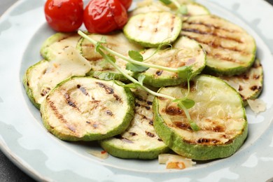 Photo of Delicious grilled courgette slices with tomatoes and microgreens on plate, closeup