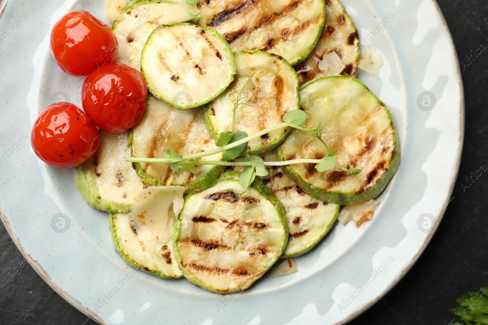 Photo of Delicious grilled courgette slices with tomatoes and microgreens on table, top view