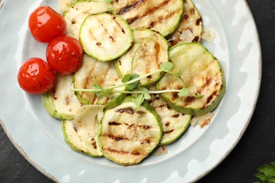 Photo of Delicious grilled courgette slices with tomatoes and microgreens on table, top view