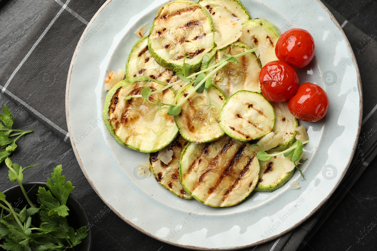 Photo of Delicious grilled courgette slices with tomatoes, microgreens and parsley on table, flat lay