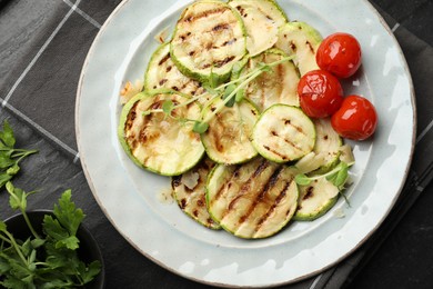 Photo of Delicious grilled courgette slices with tomatoes, microgreens and parsley on table, flat lay