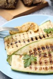 Photo of Delicious grilled courgette slices with parsley and lemon served on table, closeup
