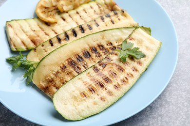 Photo of Delicious grilled courgette slices with parsley and lemon on table, closeup
