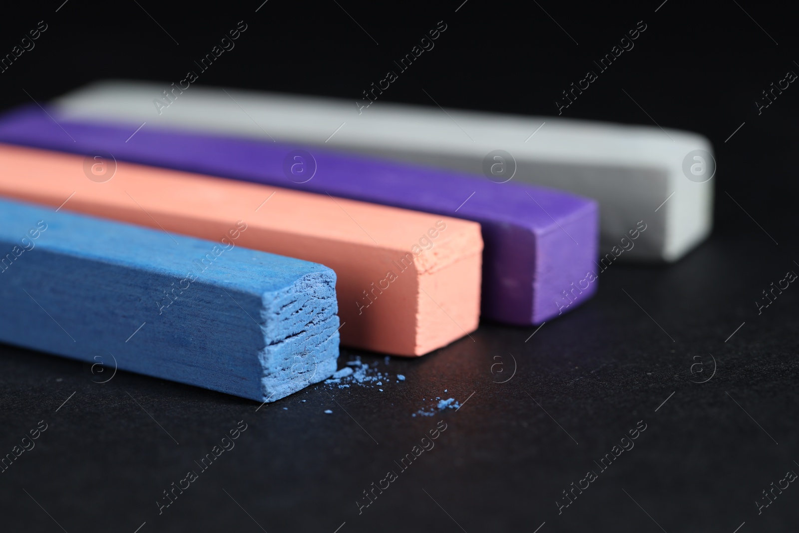 Photo of Colorful chalk pastels on black background, closeup