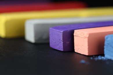 Photo of Colorful chalk pastels on black background, closeup