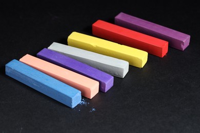 Photo of Colorful chalk pastels on black background, closeup