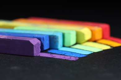 Photo of Colorful chalk pastels on black background, closeup