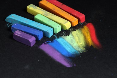 Photo of Colorful chalk pastels on black background, closeup