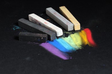 Photo of Colorful chalk pastels on black background, closeup