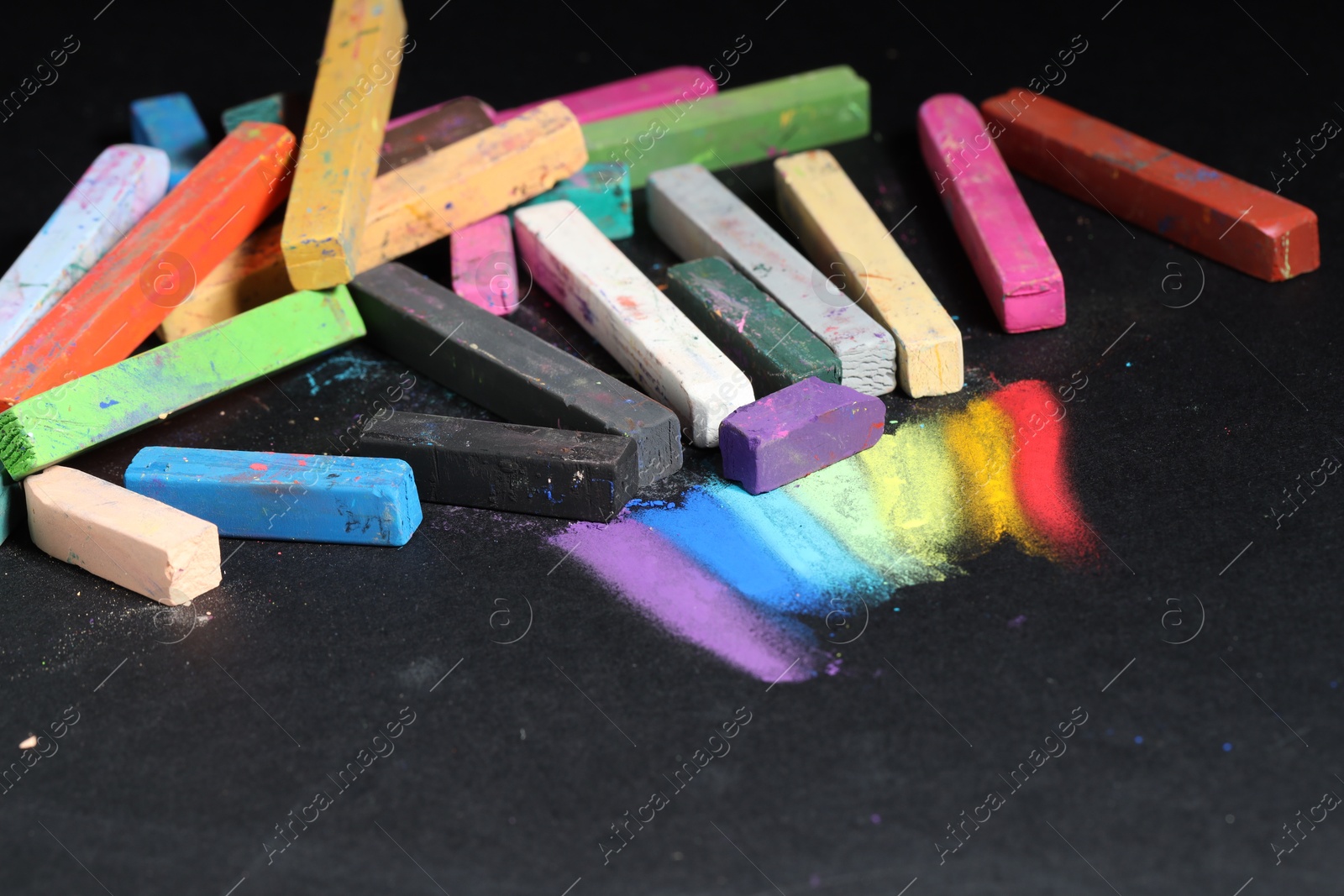 Many colorful chalk pastels on black background Photo of Many colorful chalk pastels on black background